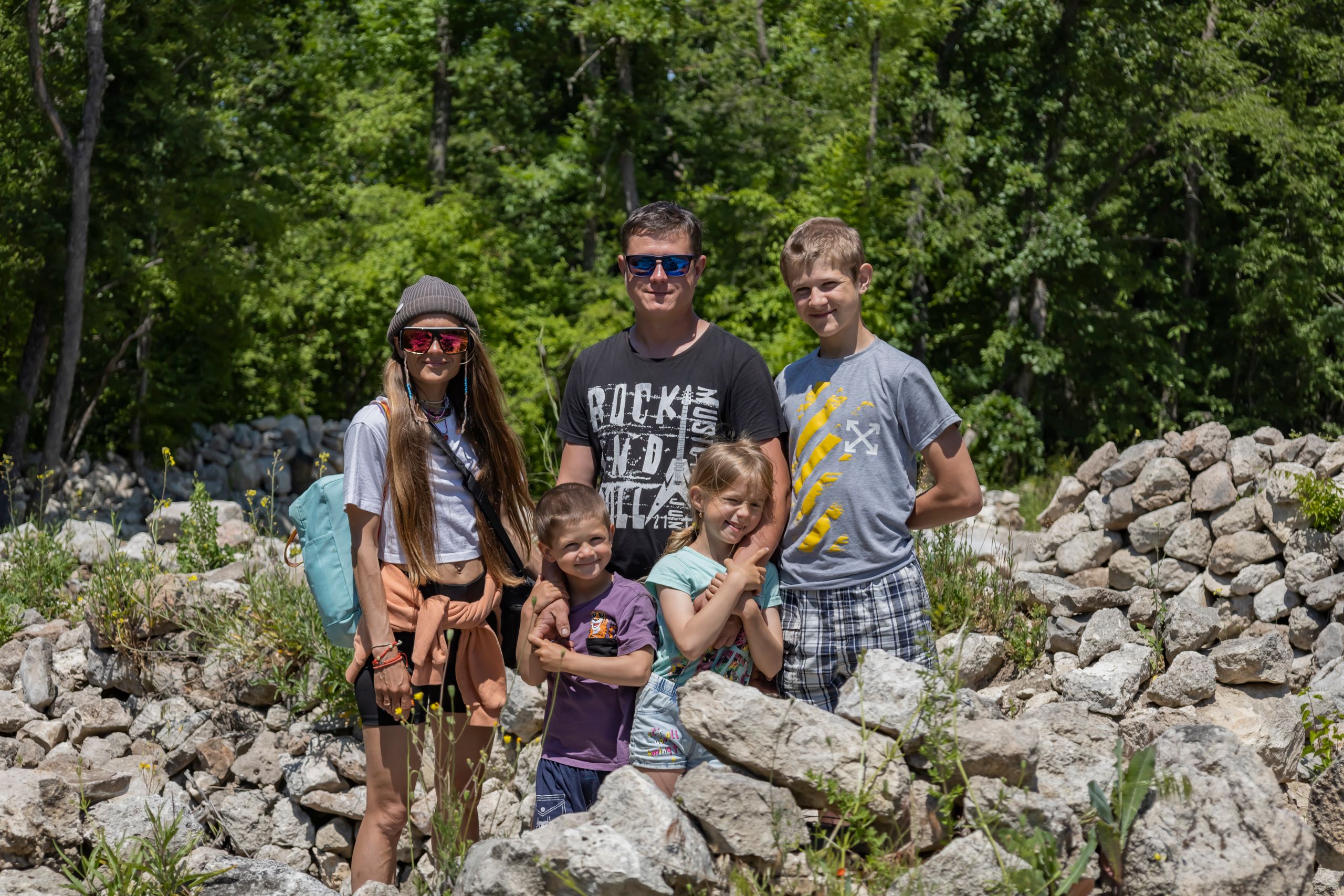 Oferty dla grup 11 A family of five bonding on a sunny outdoor adventure surrounded by rocks and greenery.