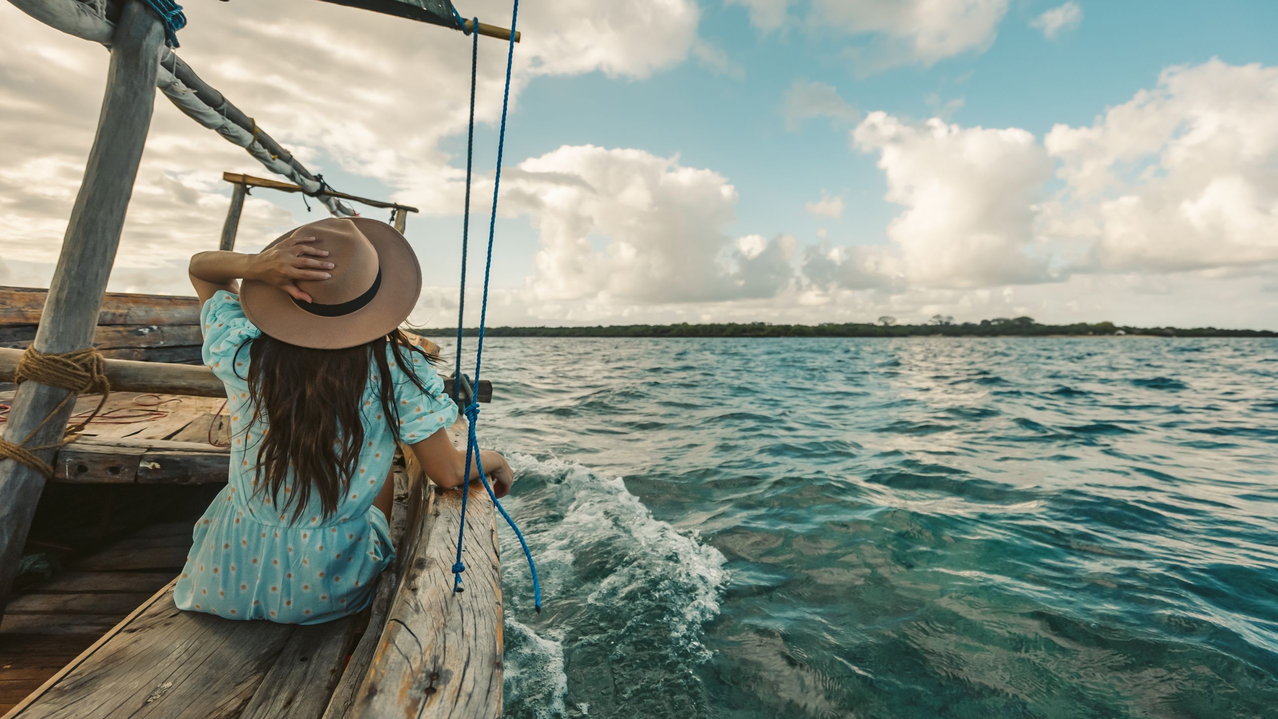 Wczasy i Wycieczki 6 A woman in a hat enjoys a peaceful boat ride on a sunny day at sea.