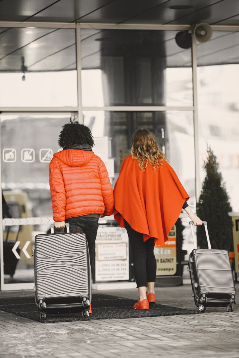 Strona główna 76 Back view of a couple in bright clothing entering an airport with suitcases.