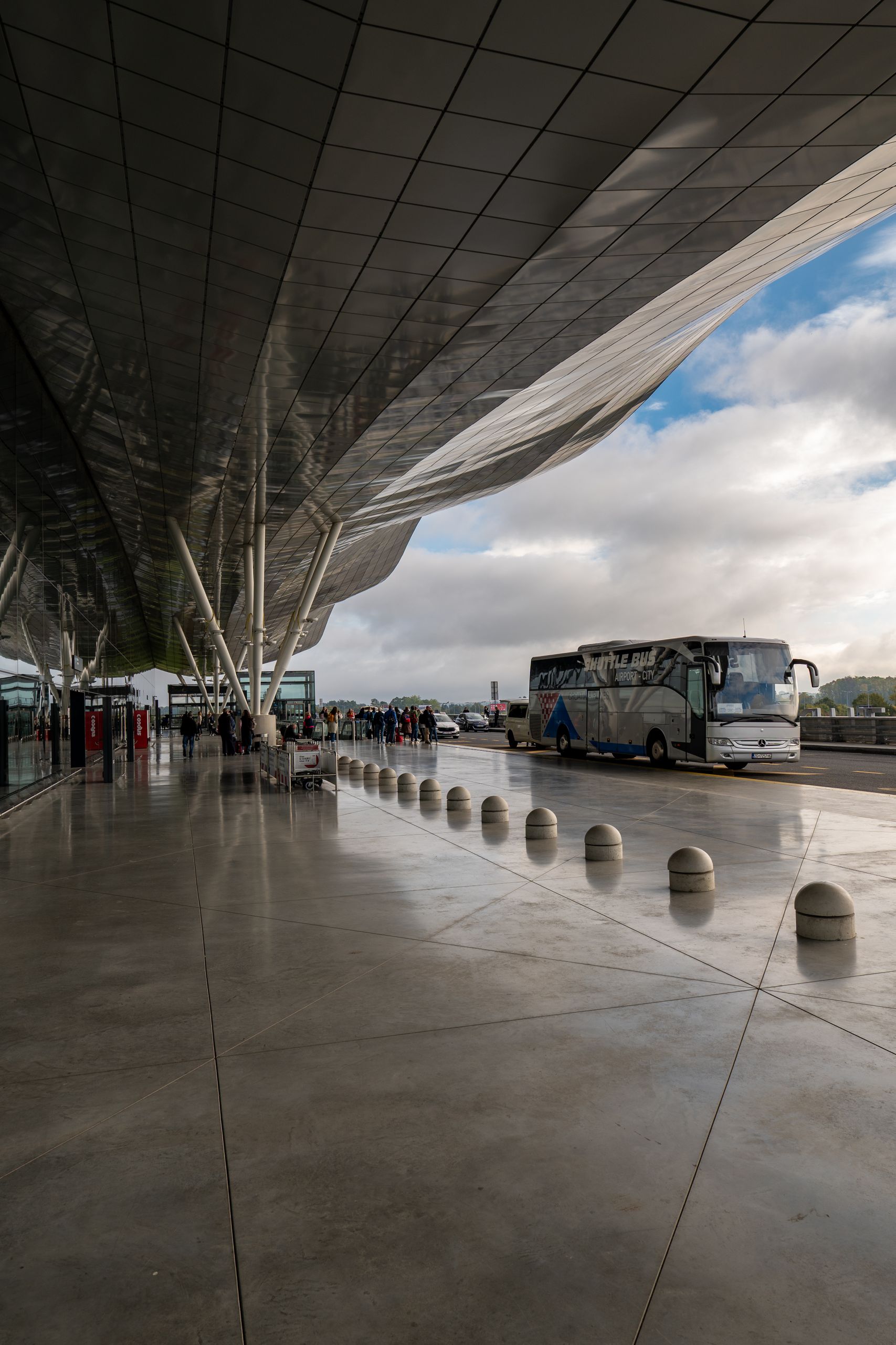 Bus terminal at Zagreb Airport showcasing modern architecture and traveling passengers.