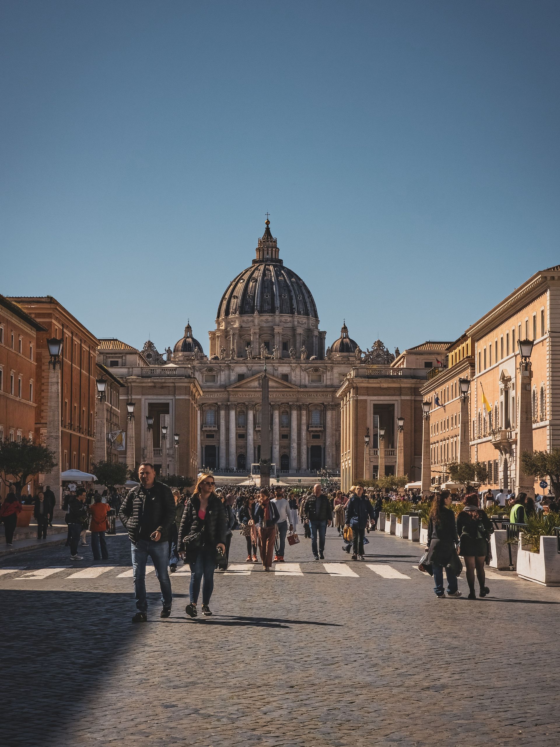 Oferty dla grup 8 Busy scene at Vatican City with people walking towards St. Peter's Basilica, showcasing iconic architecture.