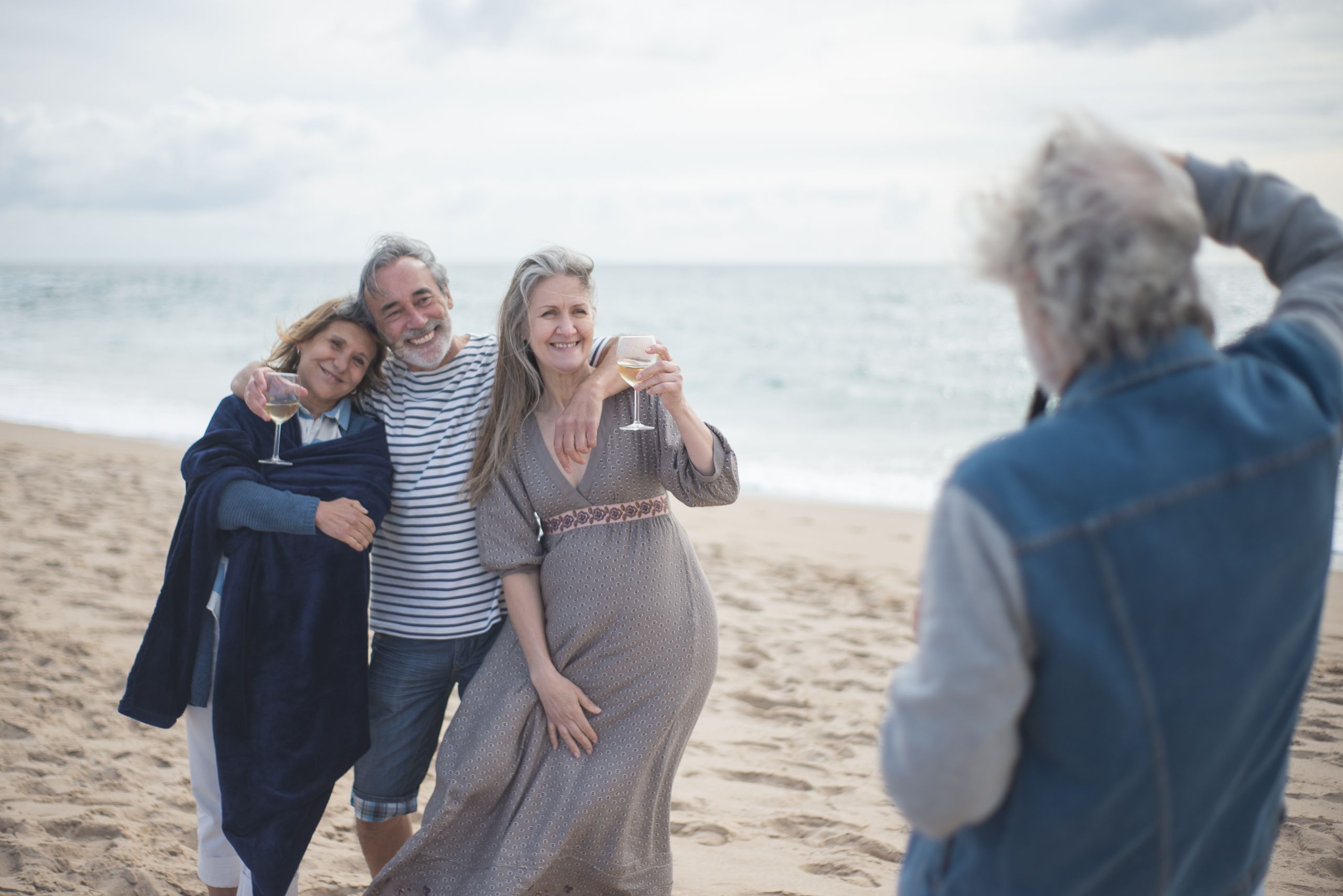 Oferty dla grup 1 Senior friends enjoying a day at the beach in Portugal, capturing memories with wine and smiles.