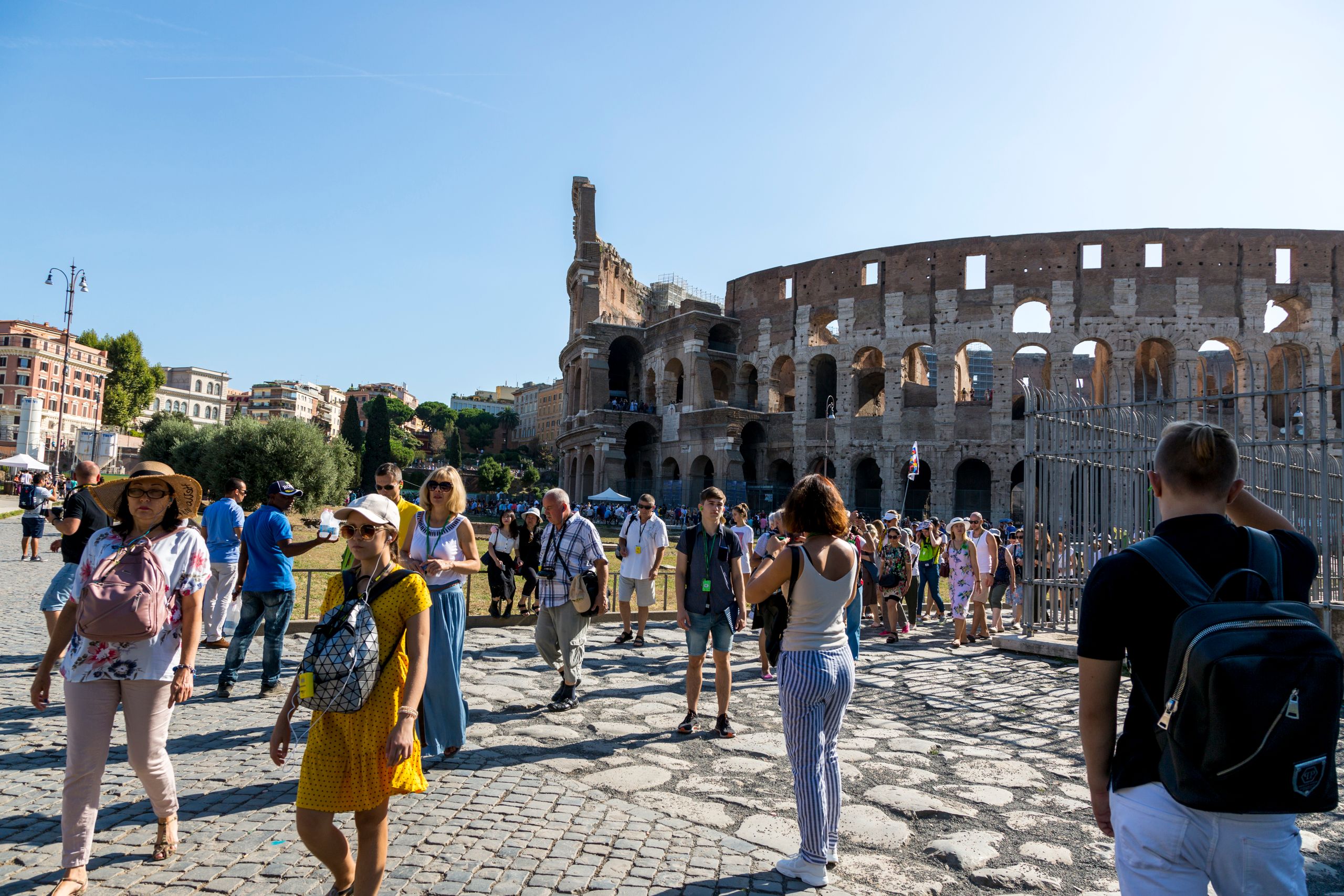 Oferty dla grup 4 Tourists wander around the iconic Colosseum in Rome on a clear summer day, capturing memories.