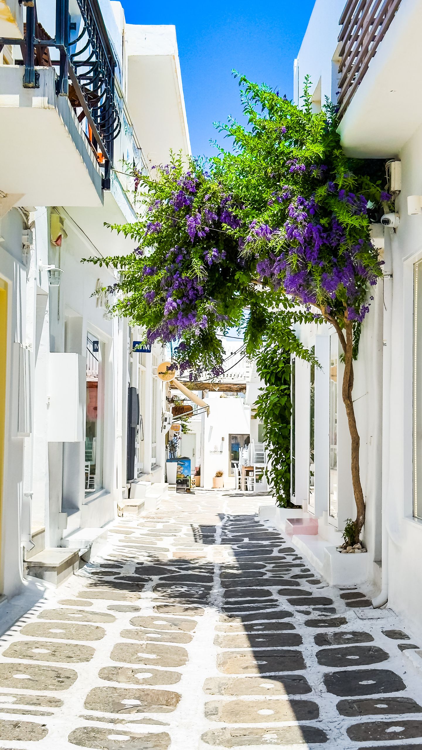 Wczasy i Wycieczki 3 Colorful alley in Mykonos with vibrant bougainvillea and traditional architecture.